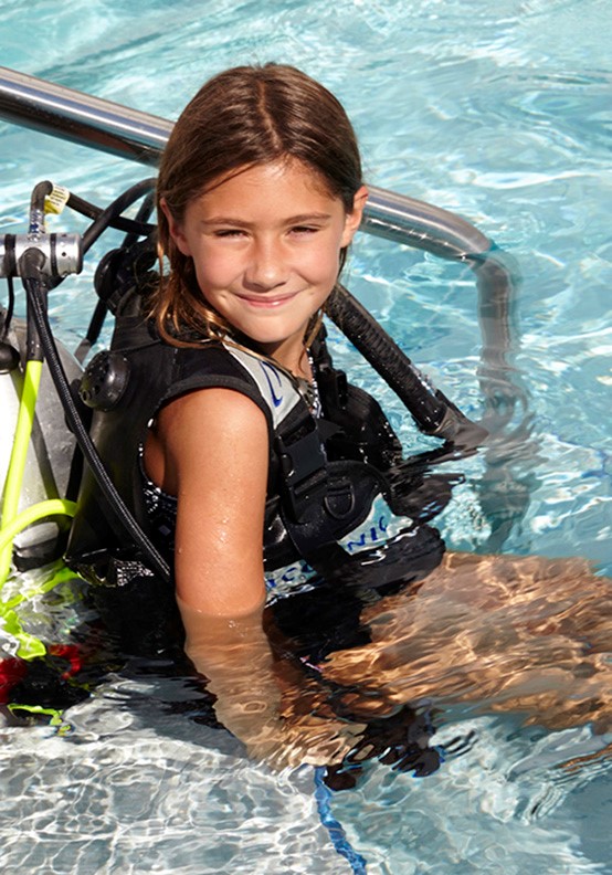 Resort lifestyle photo of little girl in the pool enjoying scuba diving lessons